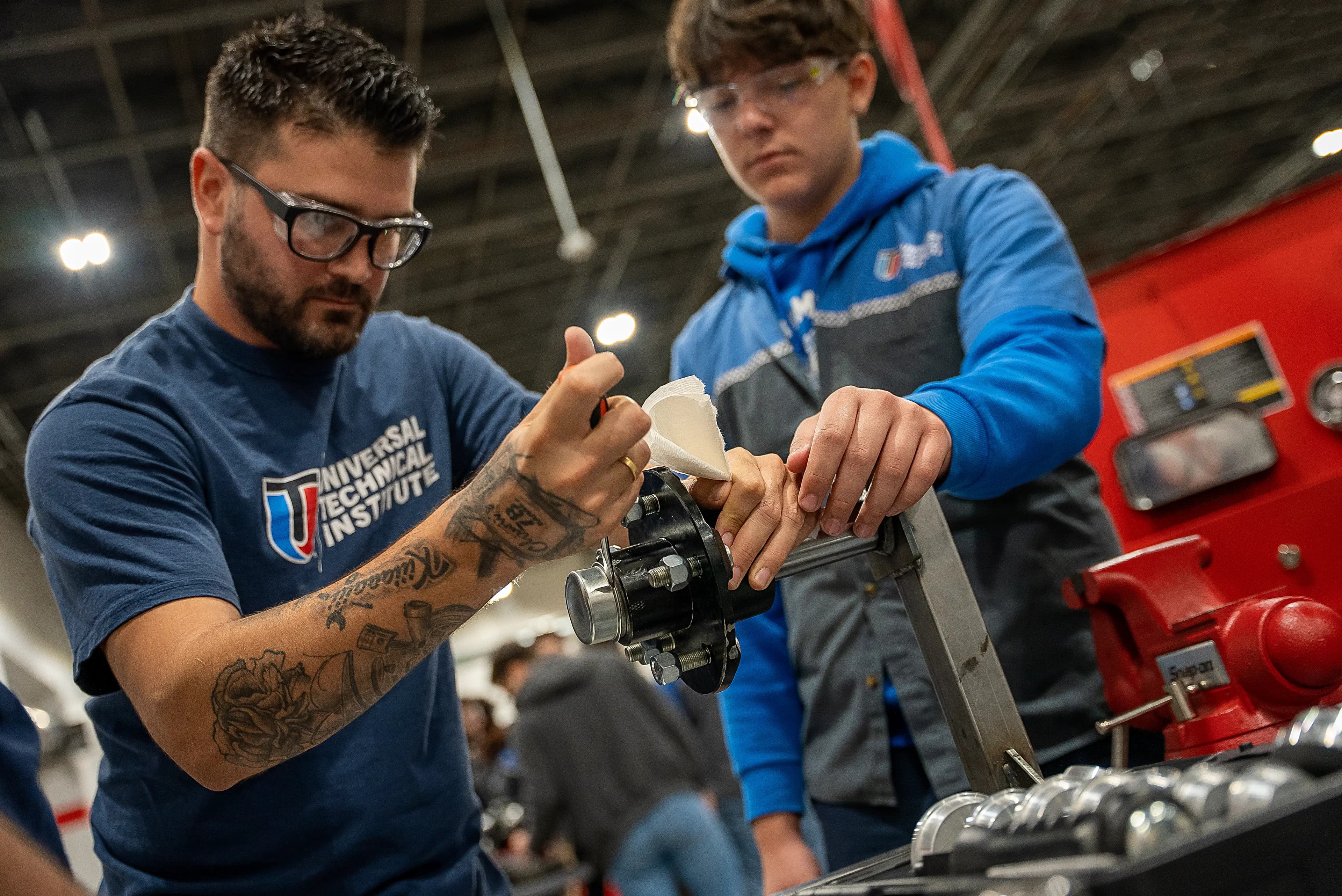 Automotive students performing hands-on engine assembly during technician training.
