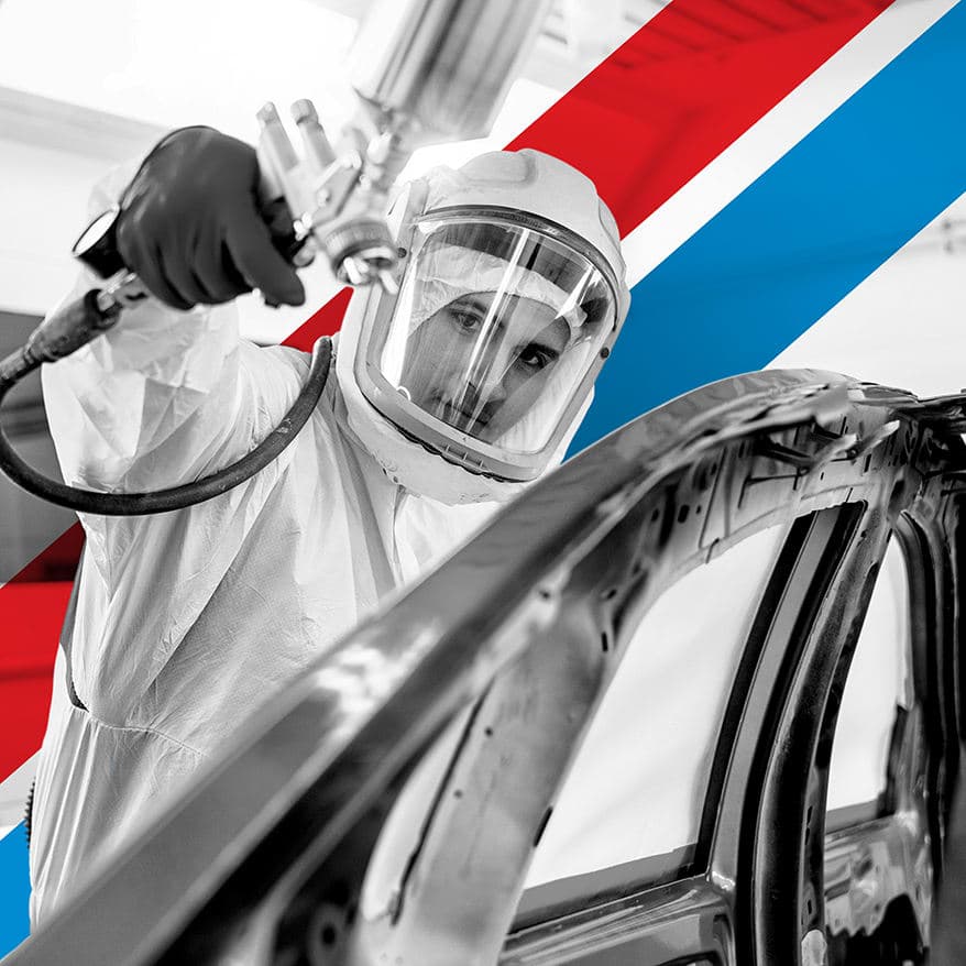UTI trade school graduate wearing a black cap and gown with honor cords, smiling at commencement ceremony.