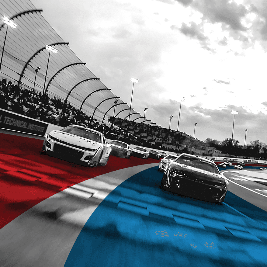 UTI trade school graduate wearing a black cap and gown with honor cords, smiling at commencement ceremony.