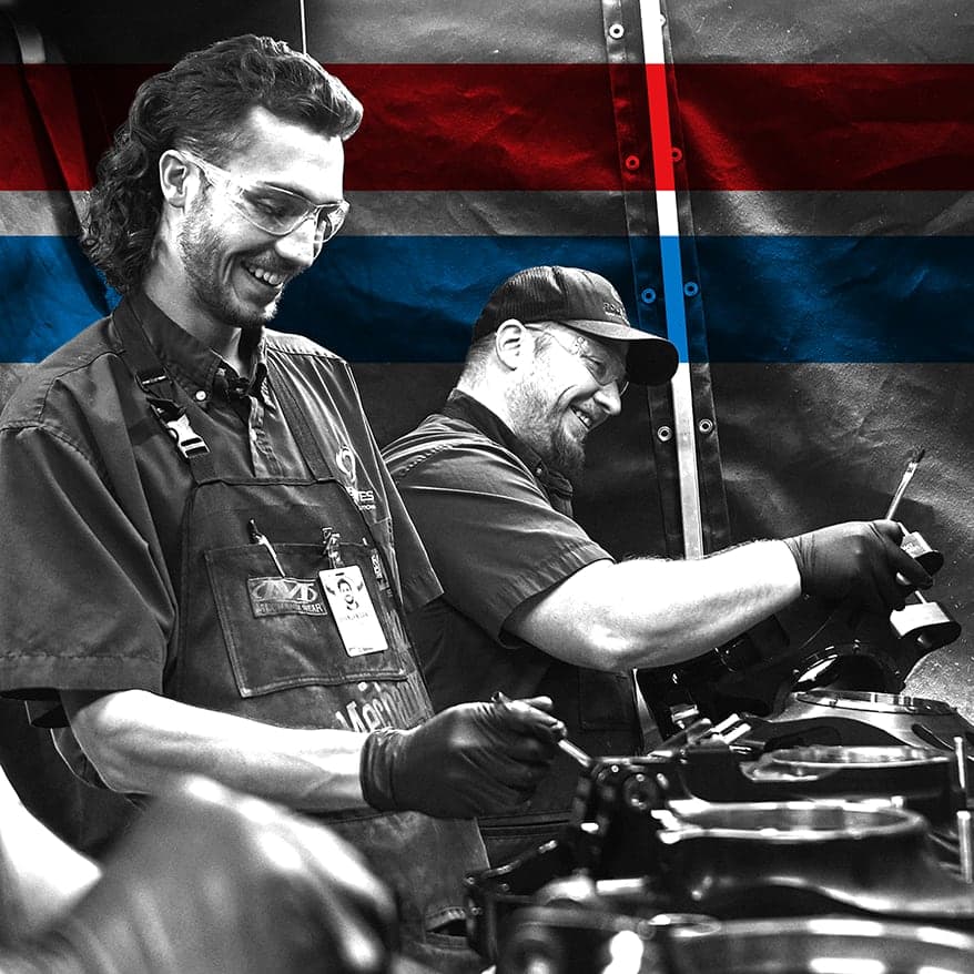 UTI trade school graduate wearing a black cap and gown with honor cords, smiling at commencement ceremony.