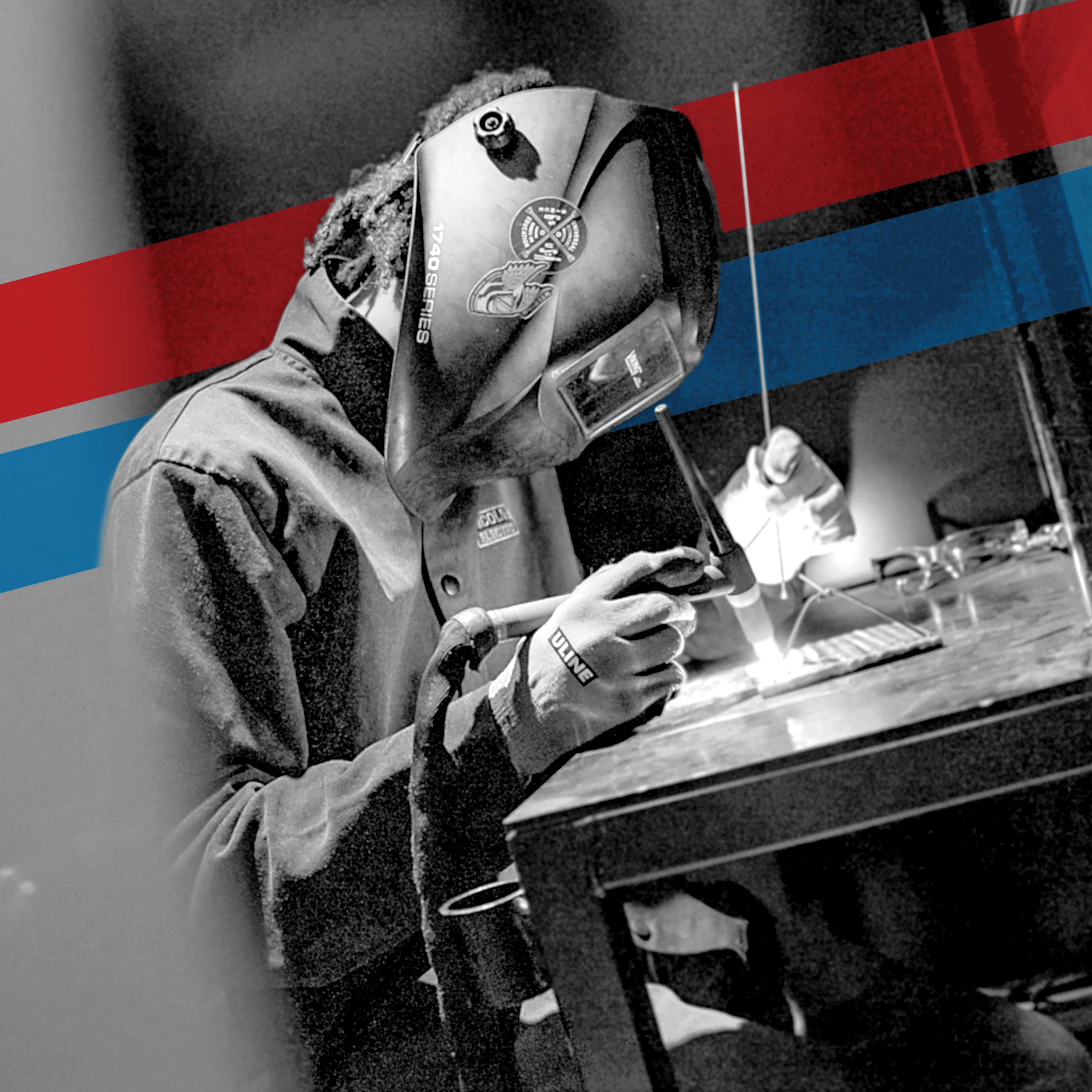 UTI trade school graduate wearing a black cap and gown with honor cords, smiling at commencement ceremony.