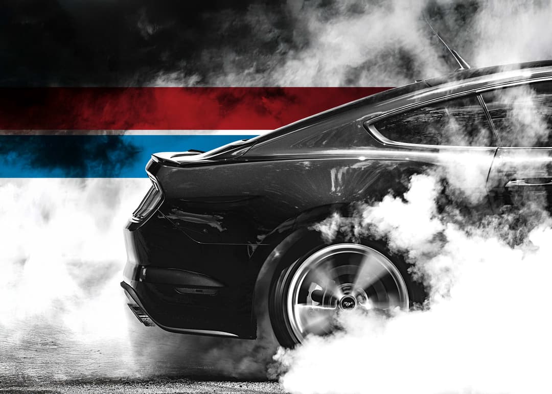 UTI trade school graduate wearing a black cap and gown with honor cords, smiling at commencement ceremony.