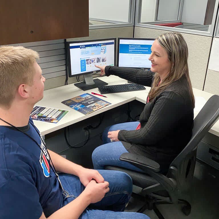 Diesel mechanic student inspecting engine belt and pulley systems during hands-on training.