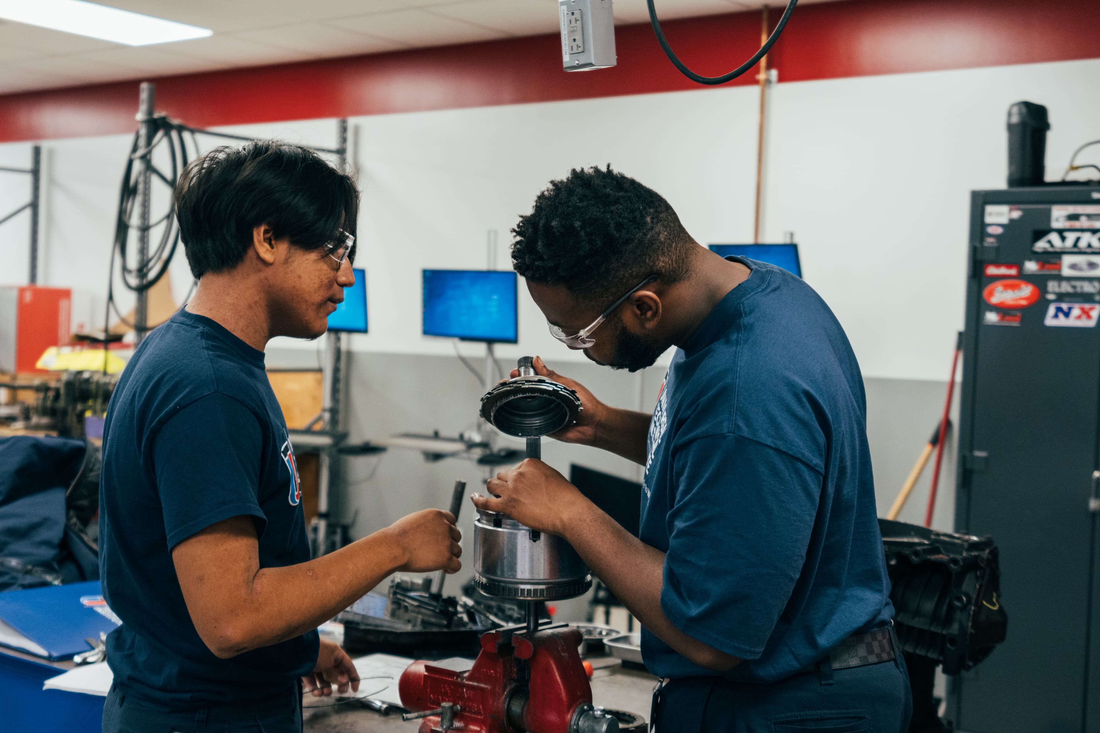 Automotive students assembling drivetrain components during hands-on technician training in a lab.