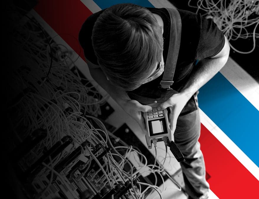 UTI trade school graduate wearing a black cap and gown with honor cords, smiling at commencement ceremony.