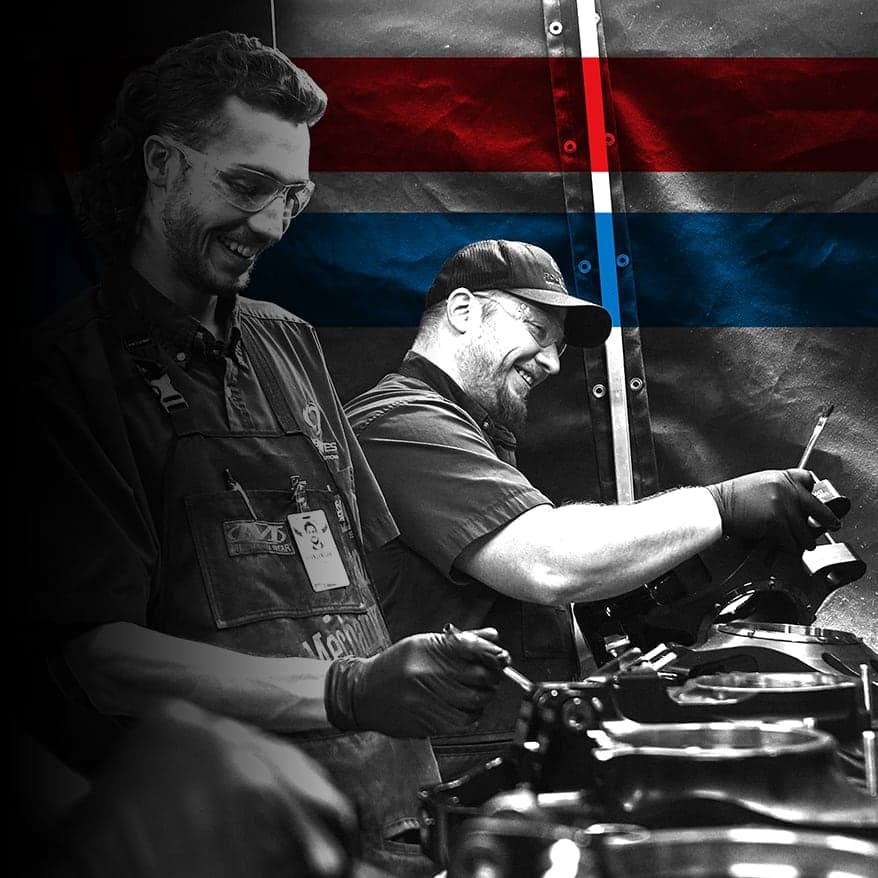 UTI trade school graduate wearing a black cap and gown with honor cords, smiling at commencement ceremony.