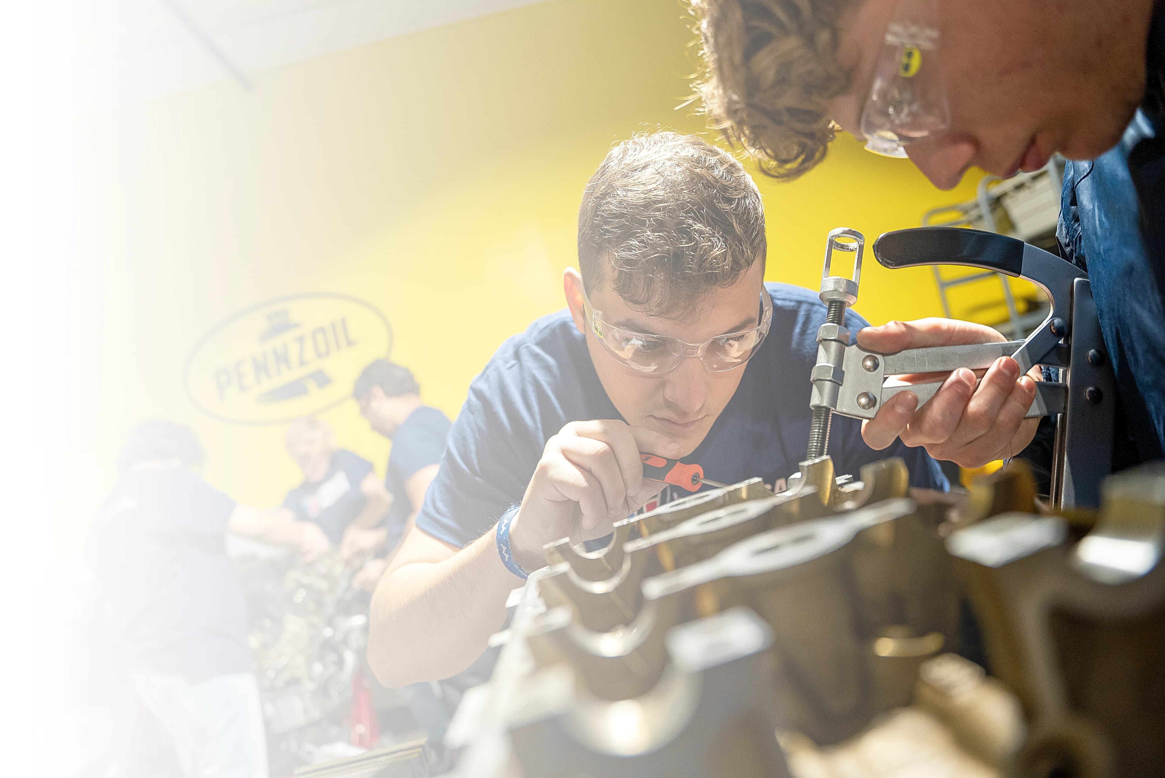 UTI trade school graduate wearing a black cap and gown with honor cords, smiling at commencement ceremony.