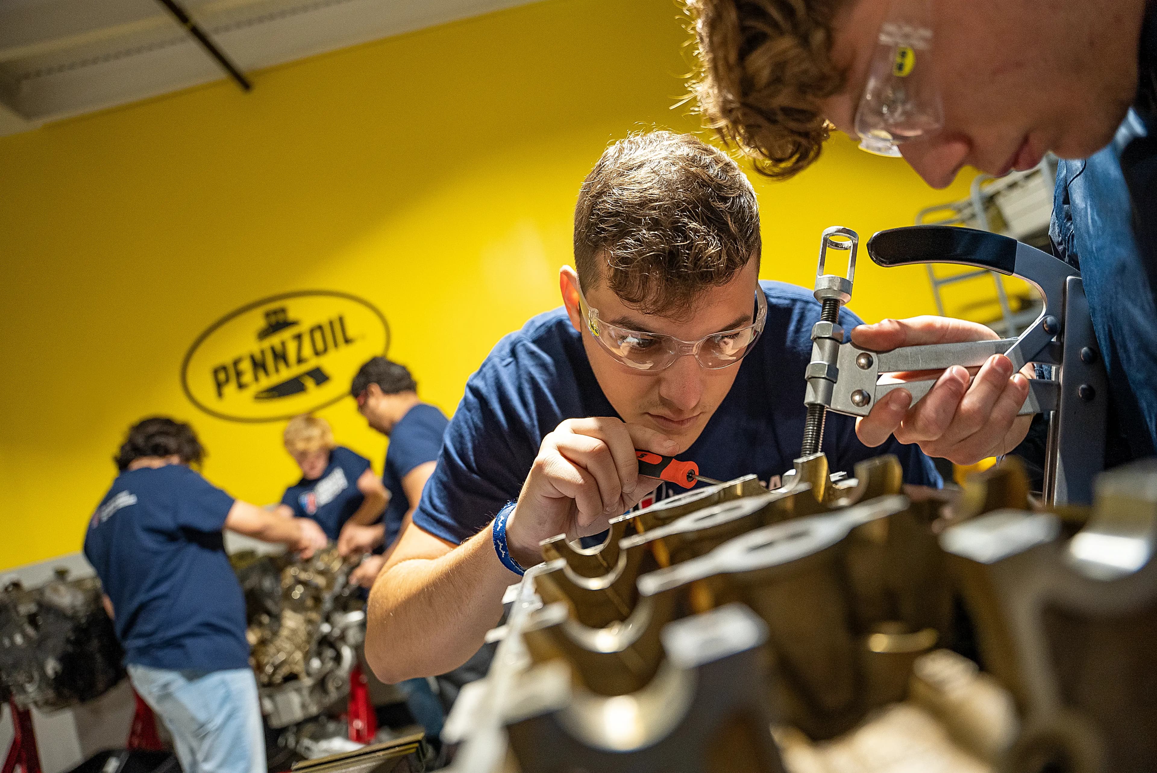 UTI trade school graduate wearing a black cap and gown with honor cords, smiling at commencement ceremony.
