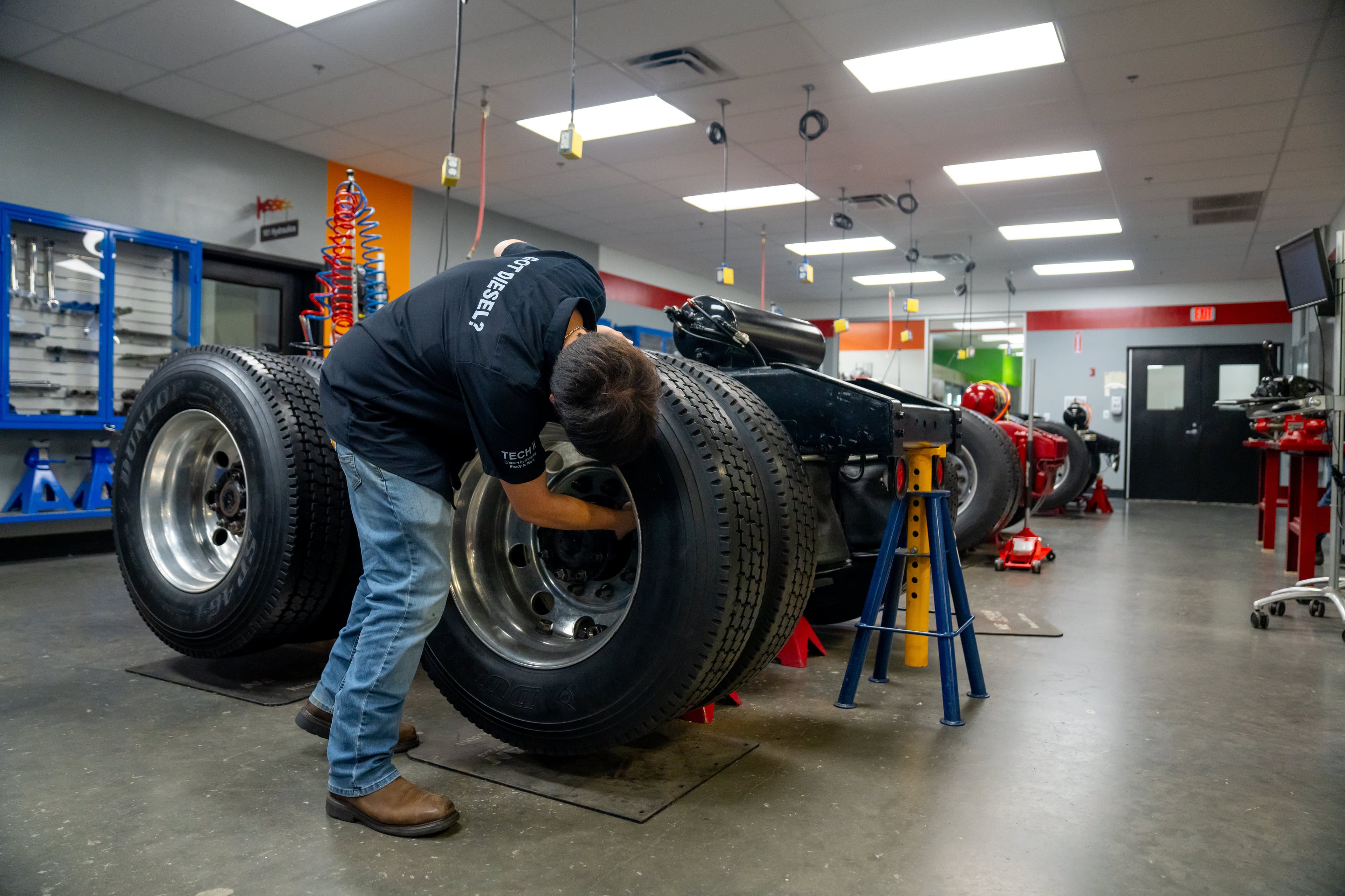 Diesel student examining heavy-duty truck wheels in a training lab.